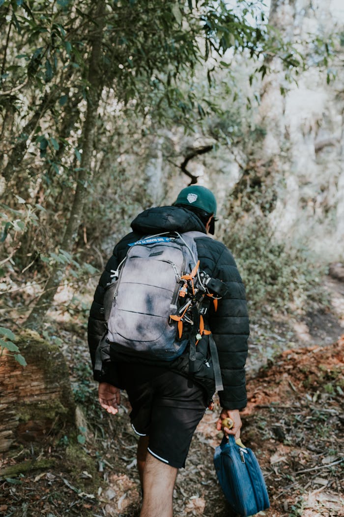 Caucasian man hiking through forest with backpack, showcasing nature exploration.